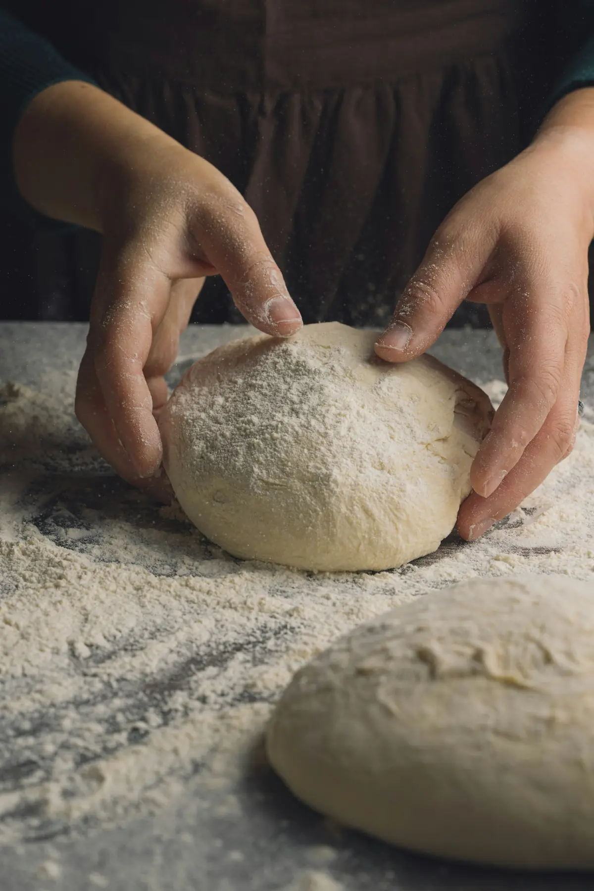 Mains de boulanger façonnant une boule de pâte farinée