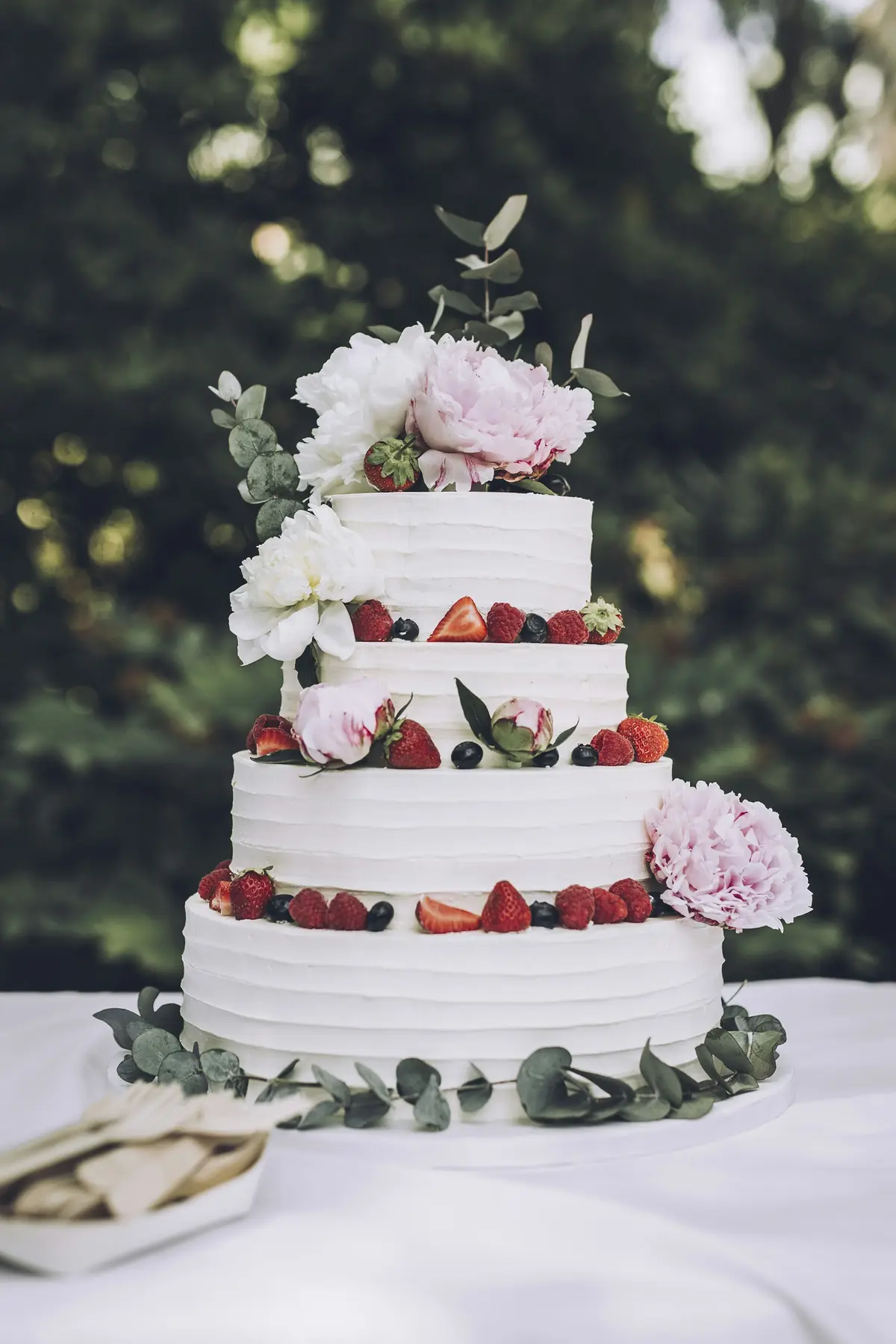 Gâteau de mariage à étages décoré de fleurs et de fruits rouges