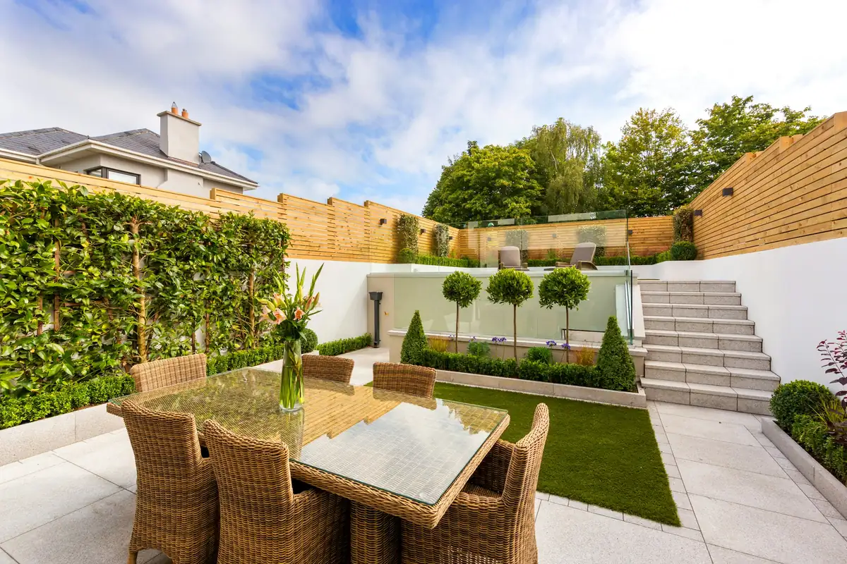 Jardin contemporain avec terrasse dallée, pelouse et arbres tiges