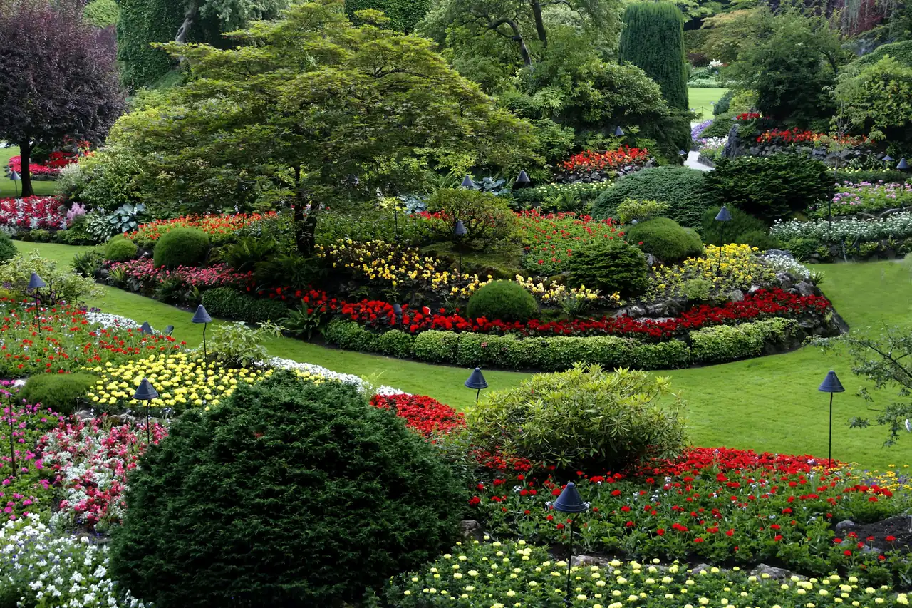 Jardin paysager fleuri avec massifs colorés et arbustes taillés