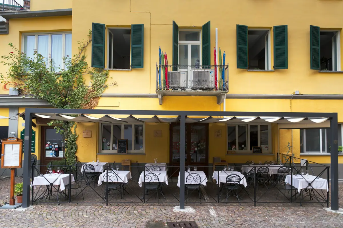 Terrasse d'été sous un store, devant une façade jaune