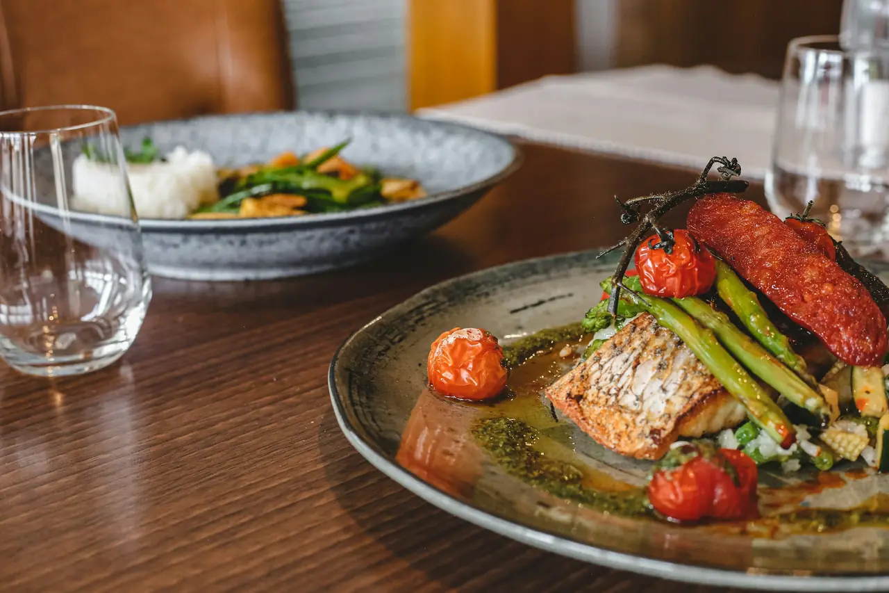 Filet de poisson, asperges et tomates rôties dressés dans une assiette